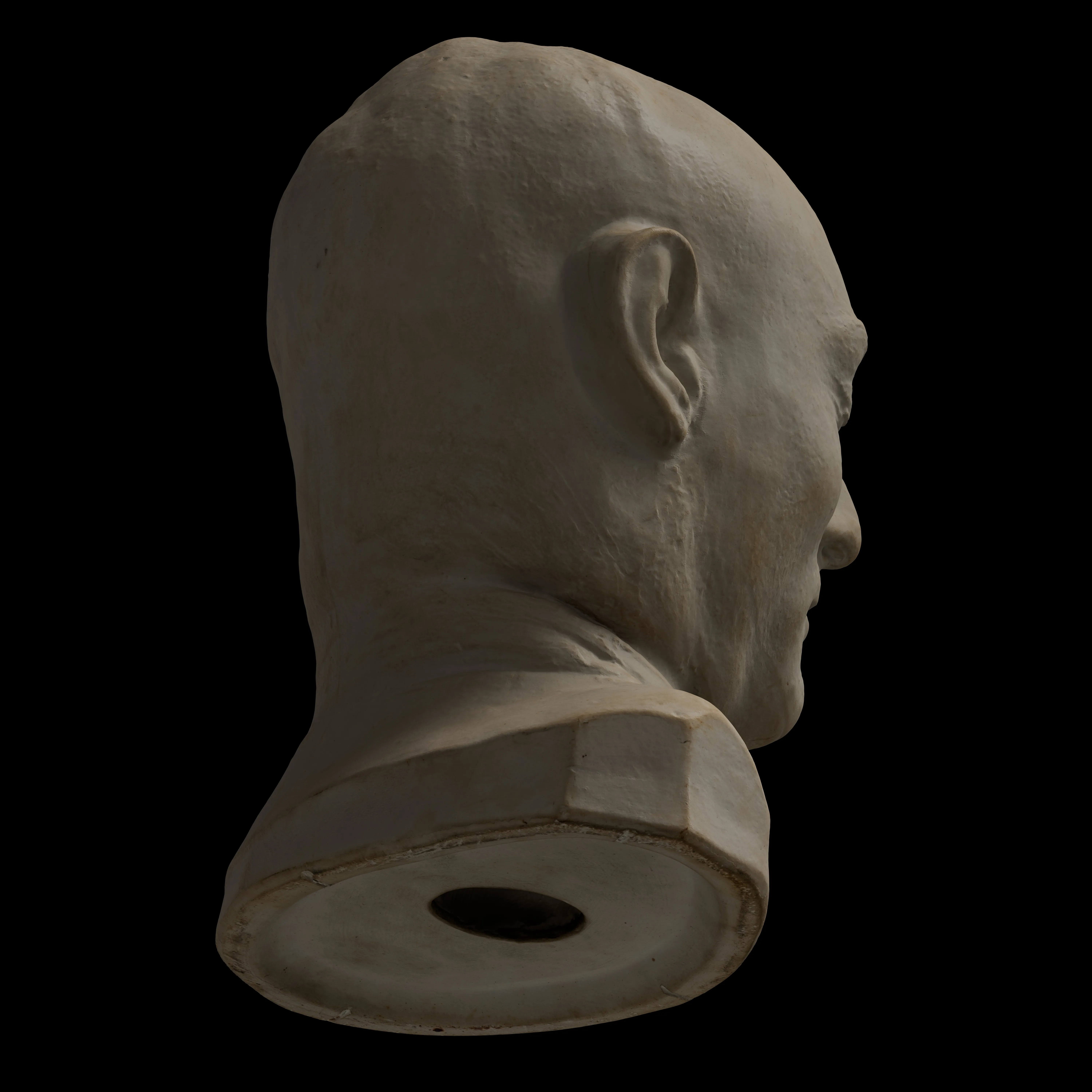 Side view of a pale death mask sculpture of a bald man's head, floating on a black background.
