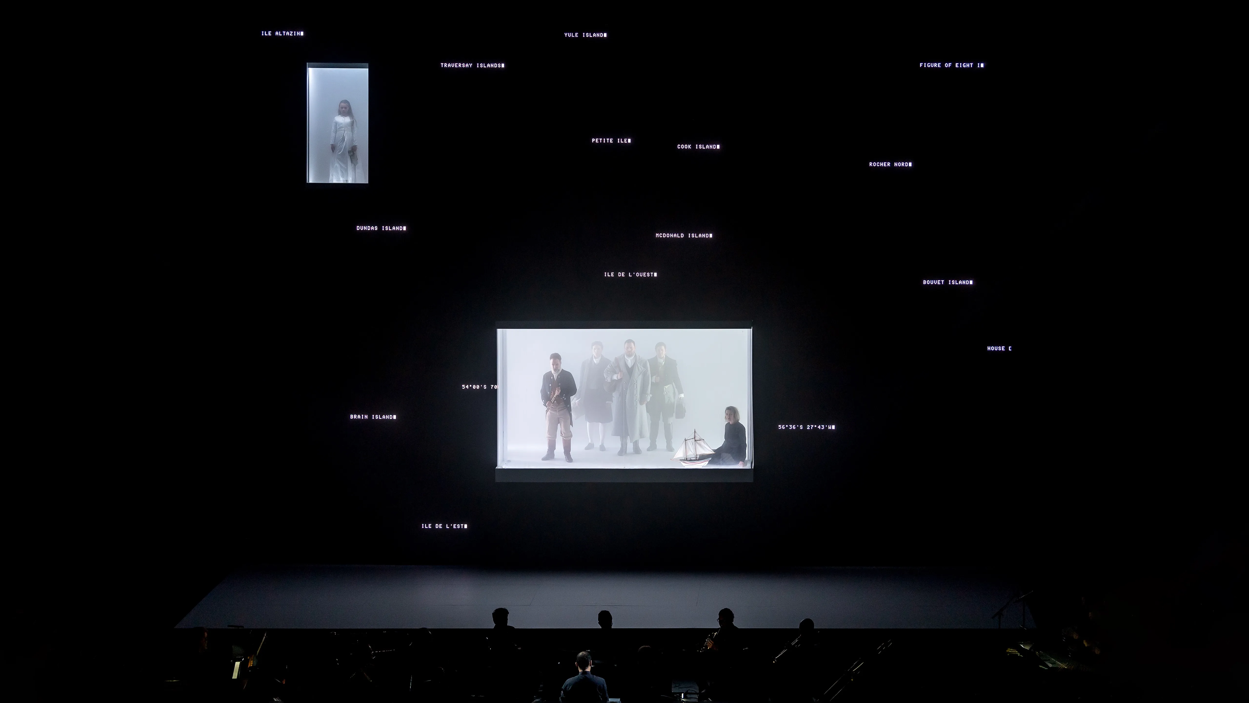 Five opera singers in a glass enclosure filled with light fog and surrounded by a large LED screen displaying coordinates and the names of locations.