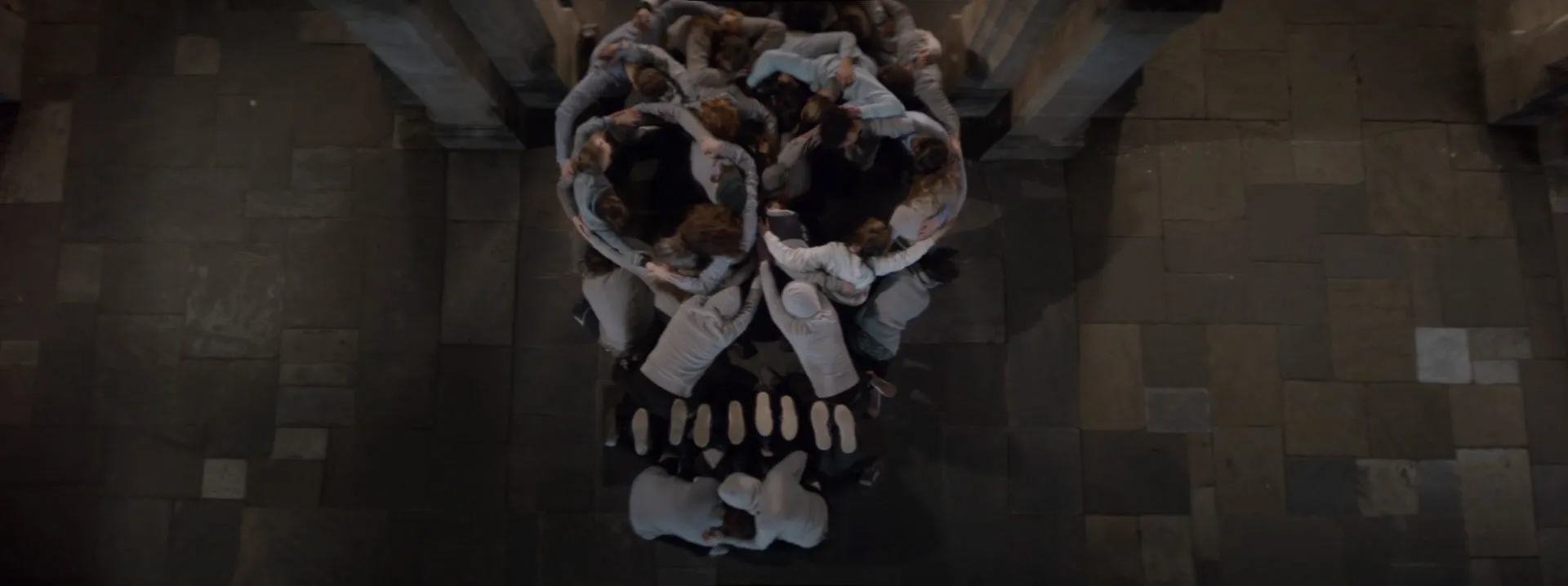 Dozens of bodies are bunched together, forming the shape of a skull.