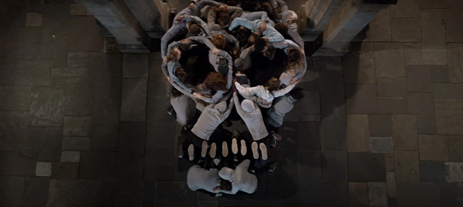A mass of performers intertwined and suspended together in a dimly lit room.