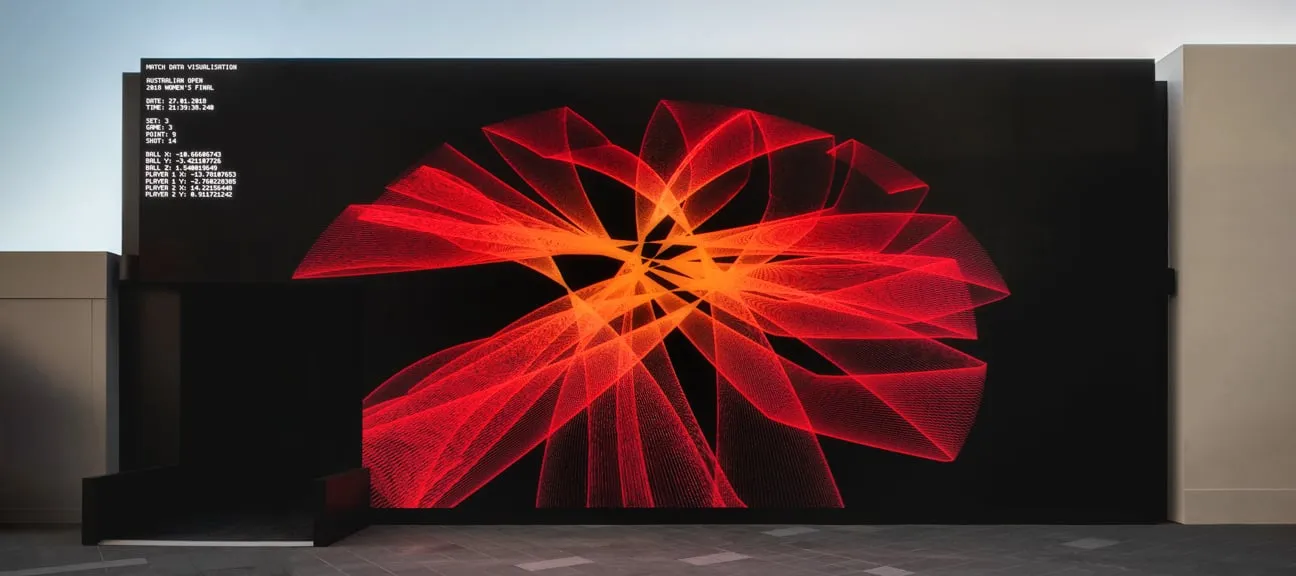Red and orange generative lines forming an abstract shape on a large outdoor screen