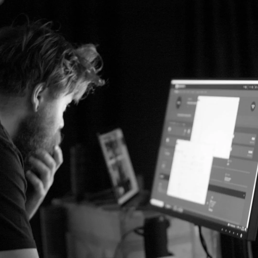 Person examining photogrammetry processing software on a computer monitor in a darkened studio.