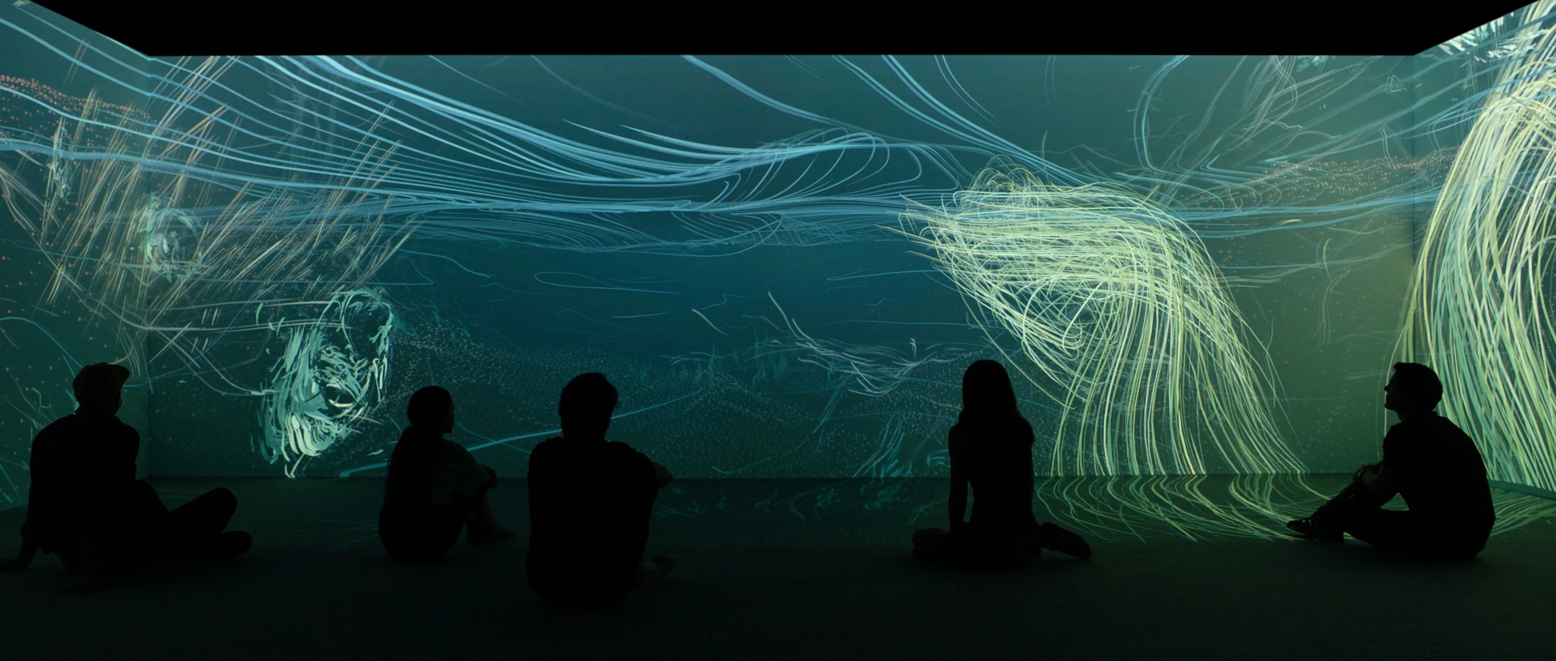 Museum visitors silhouetted against an immersive projection of flowing blue and green lines