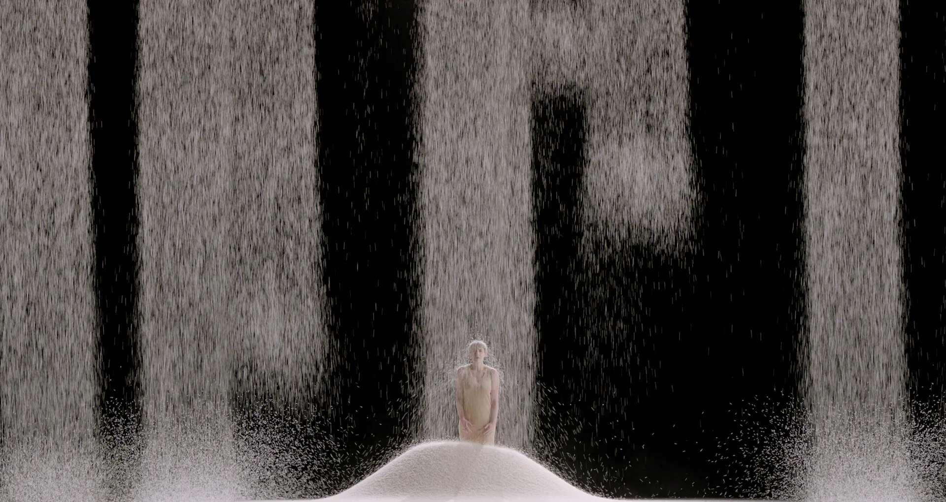 Streams of rice fall from high above onto a woman.