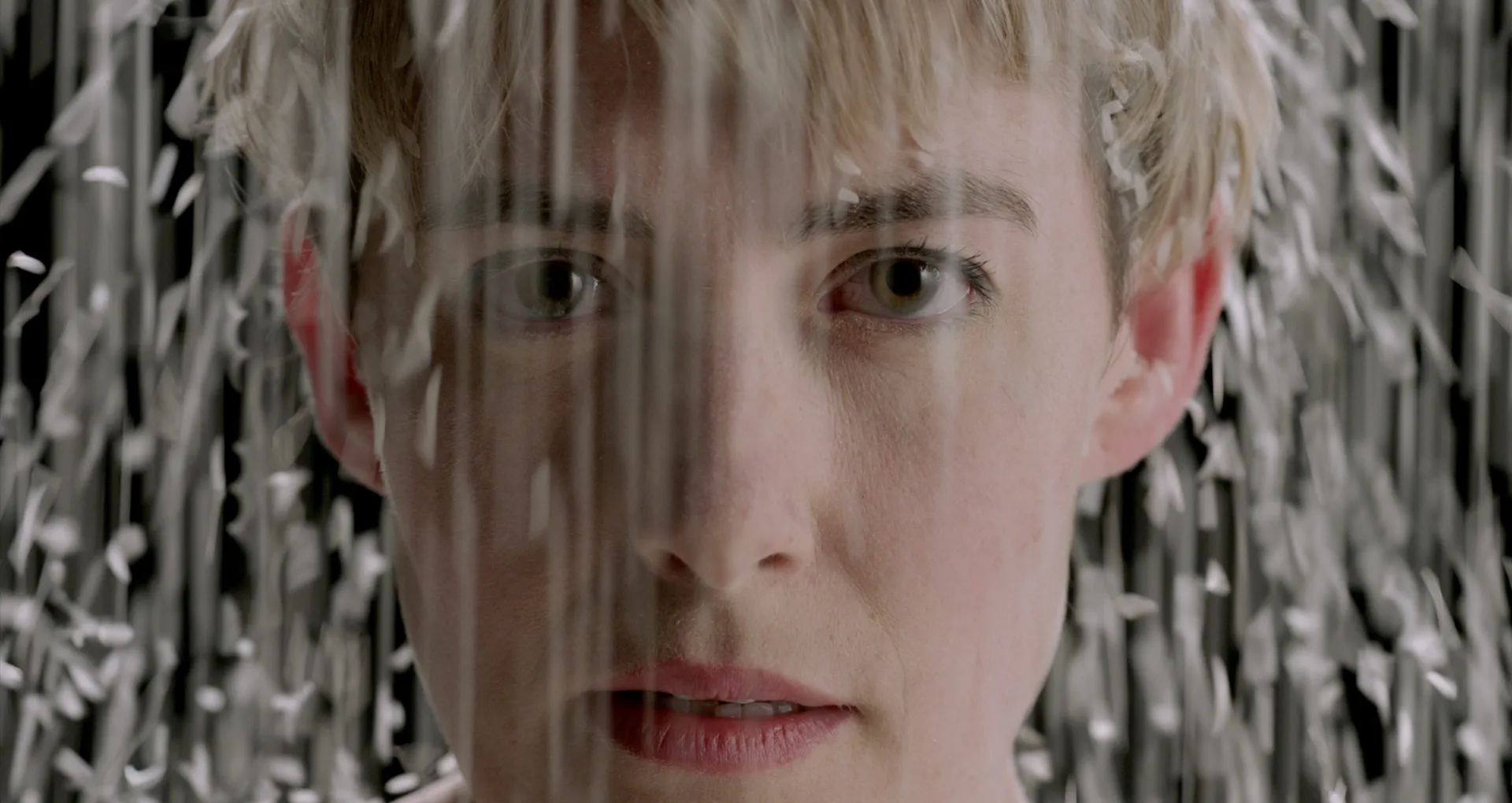 Close-up of a woman's face as rice falls onto her from above.
