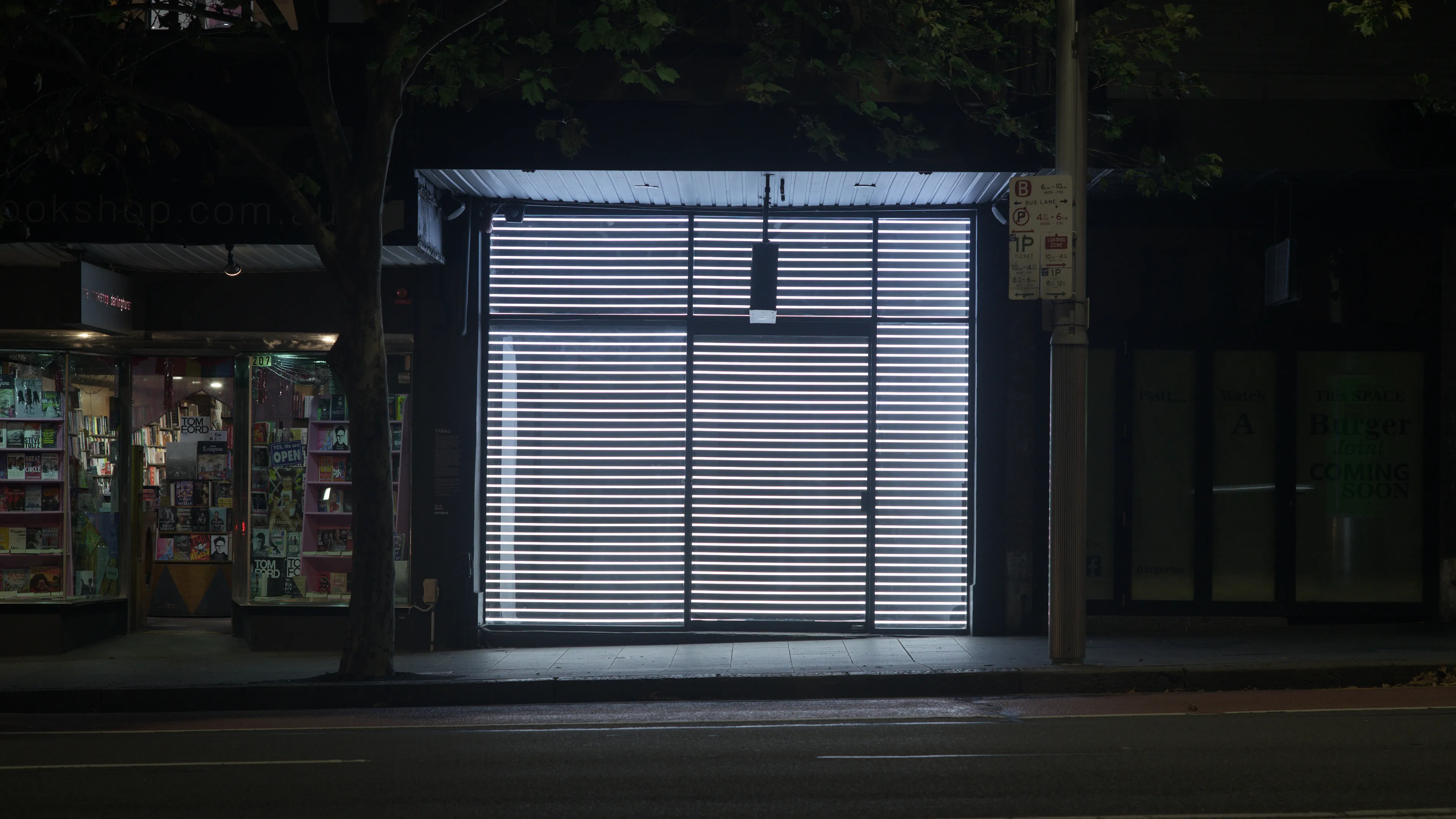 A shopfront window on a street at night, filled with horizontal strips of light.