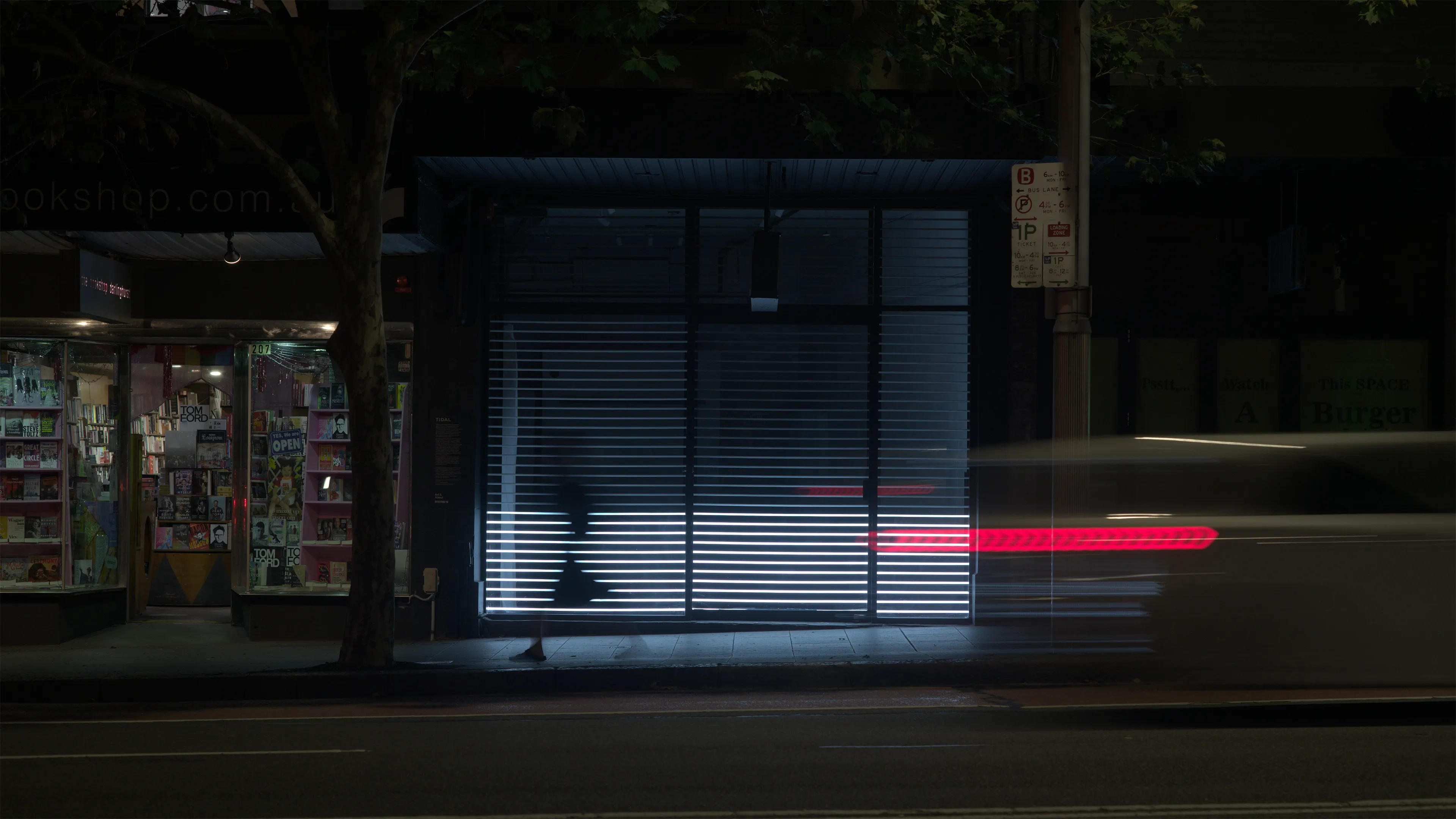 A car driving and a woman walking pass by the light installation artwork.