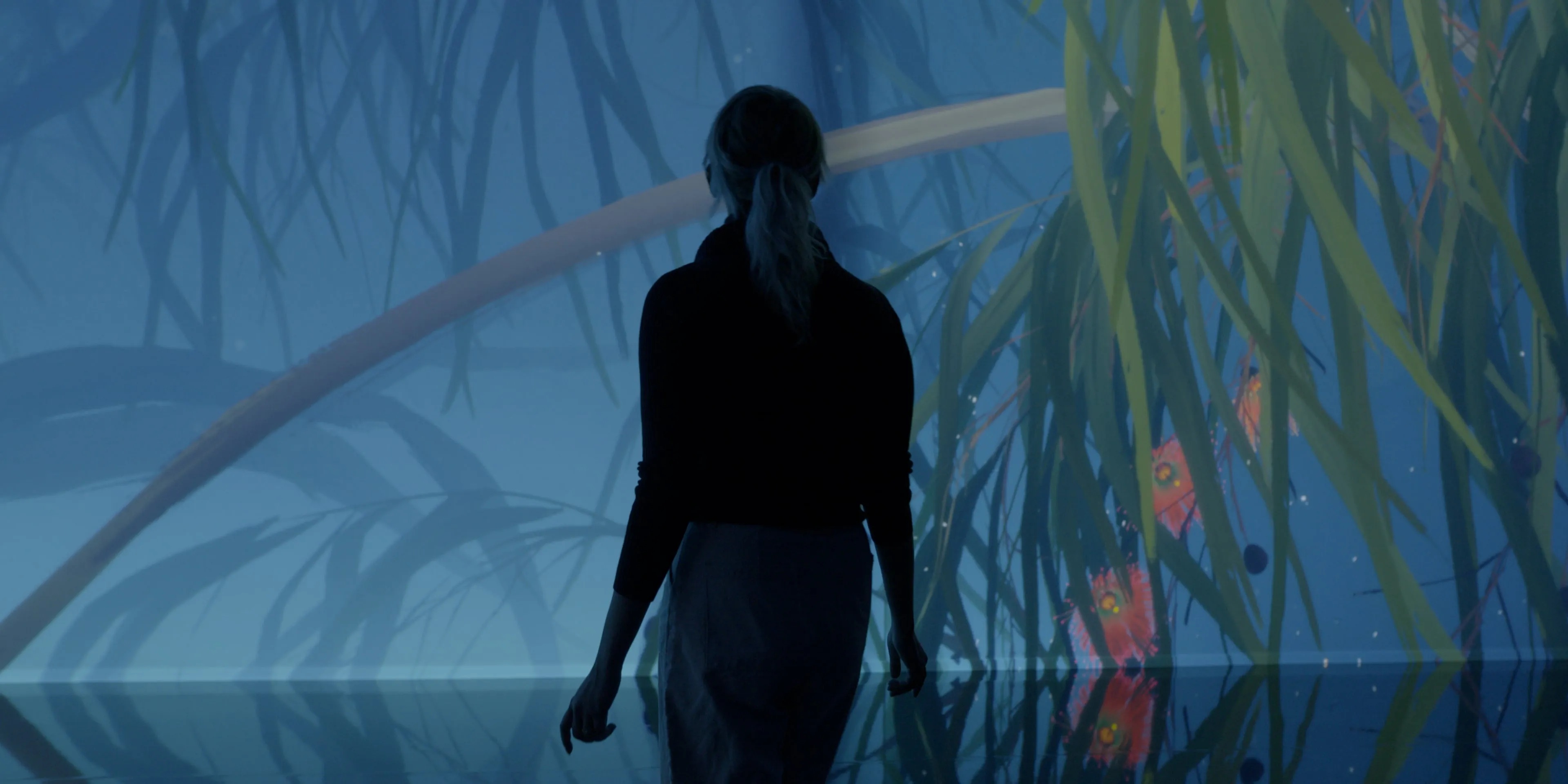 Woman silhouetted against an immersive projection of native plants and flowers