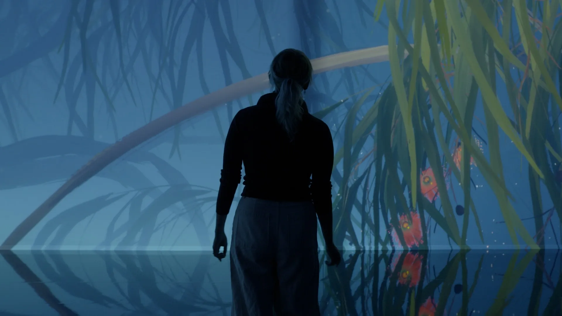 Visitor standing before an immersive projection of large plants and glowing forms in a blue environment.